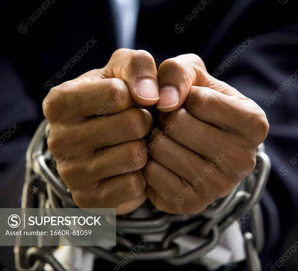 Businessman's hands bound in chains