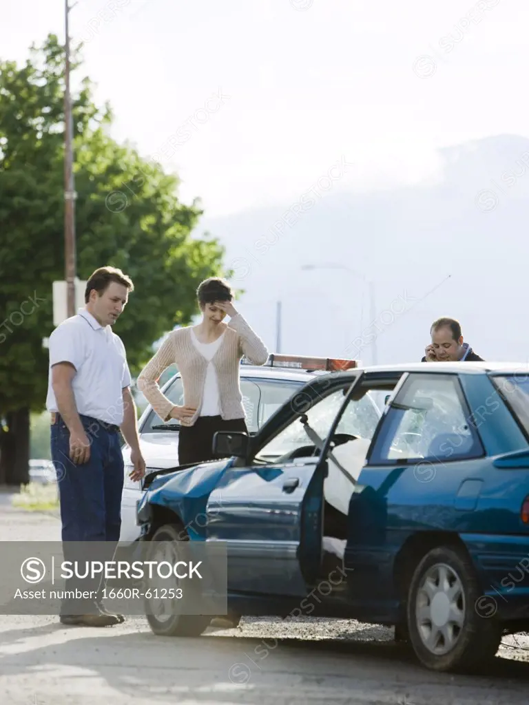 people looking at a car after an accident