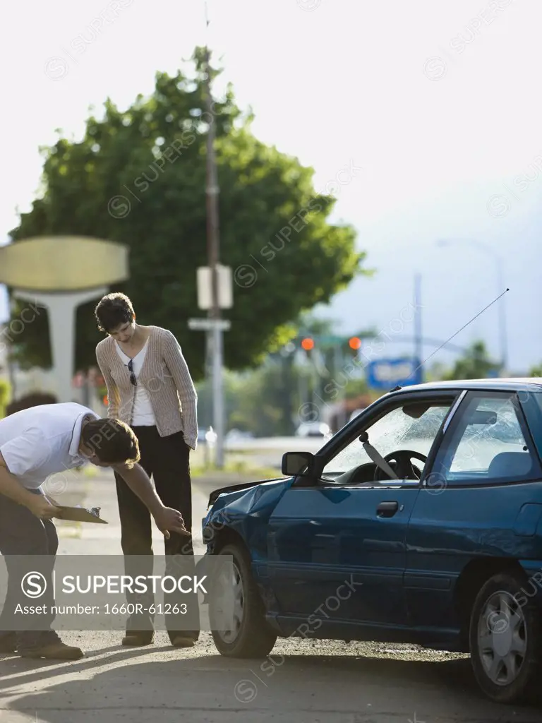 people looking at a car after an accident