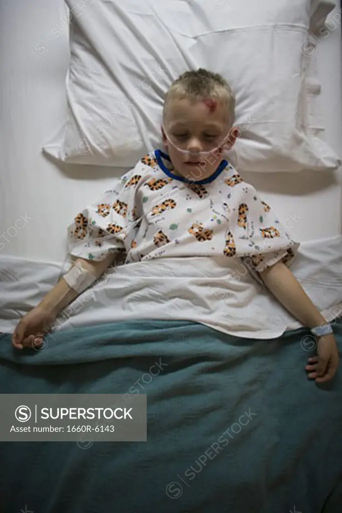 High angle view of a boy lying in a hospital bed breathing through a tube