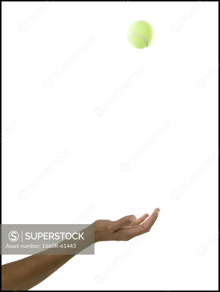 hand tossing a tennis ball