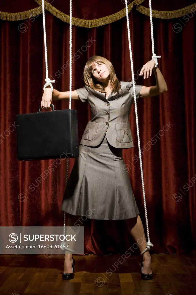 businesswoman being pulled by strings like a puppet