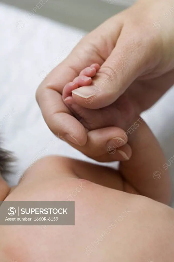 High angle view of a newborn baby holding a person's hand