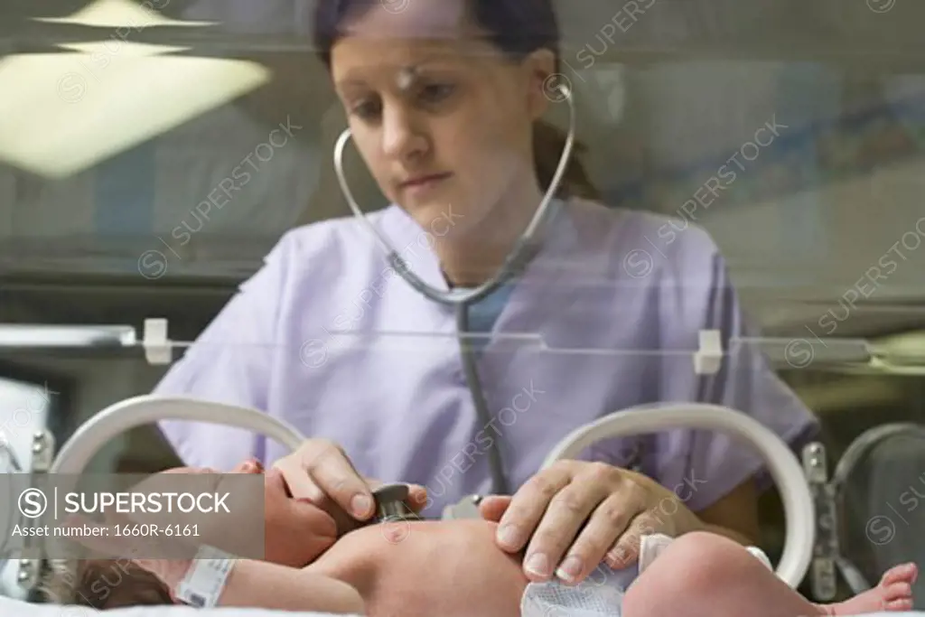 Female nurse examining a newborn baby with a stethoscope