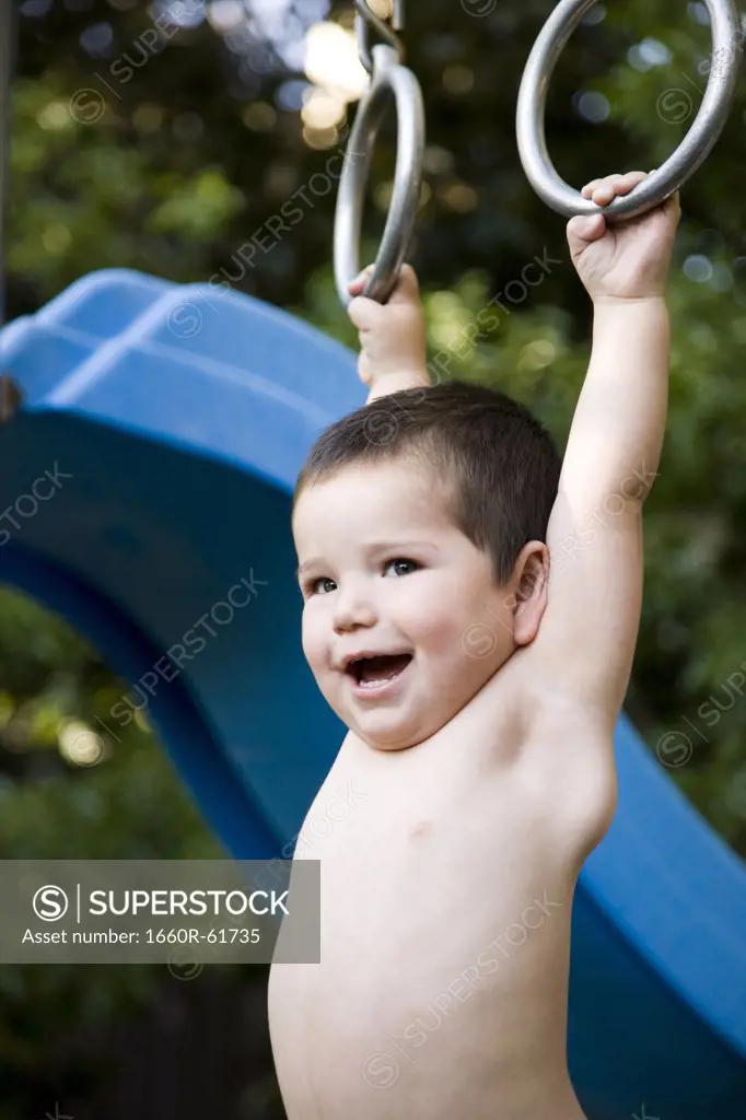 little boy hanging from a jungle gym