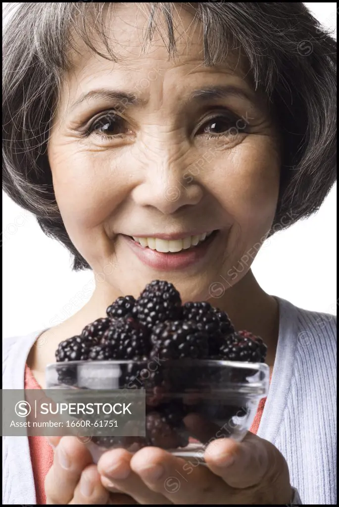 woman holding up a bowl of blackberries