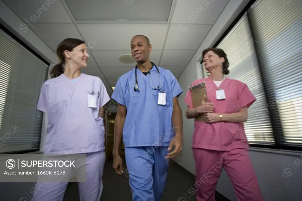 Low angle view of a male doctor and two female doctors walking in a corridor