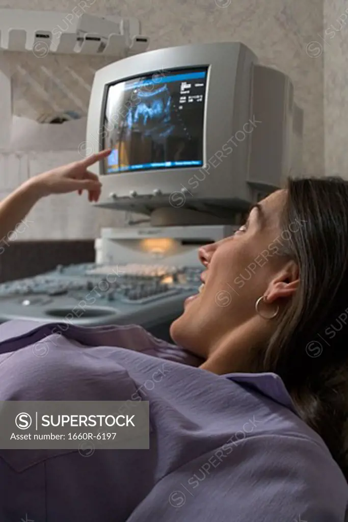 Pregnant woman lying on a hospital bed looking at her ultrasound result