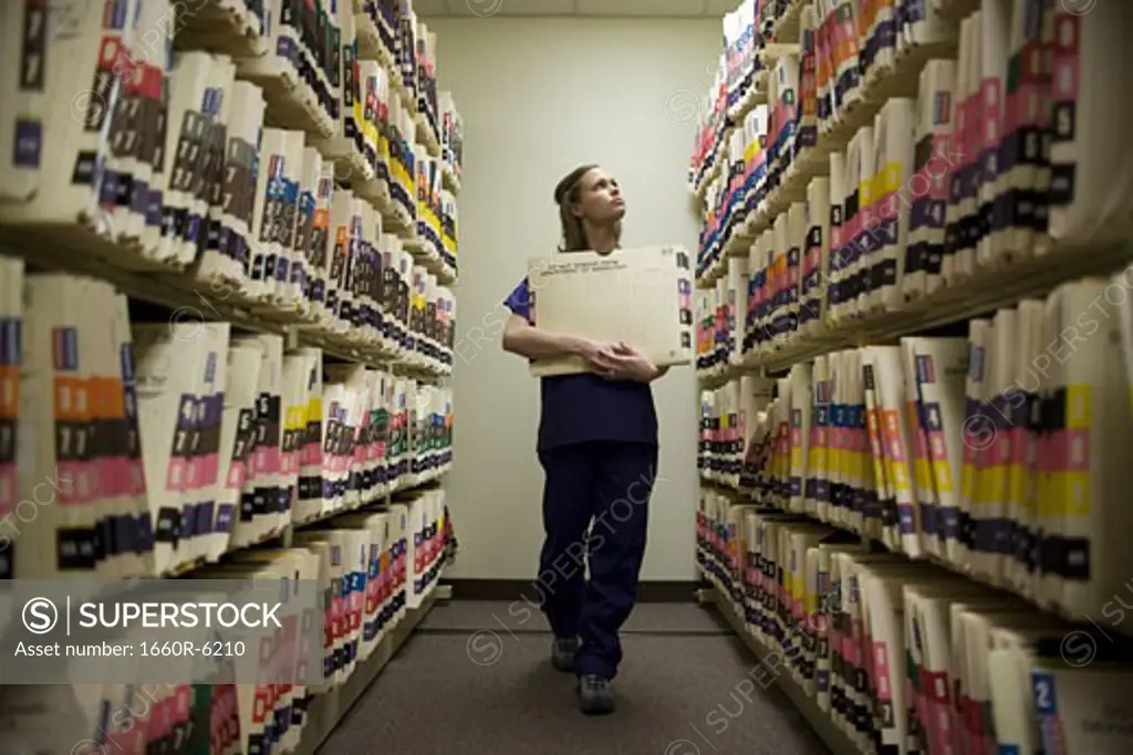 Female nurse searching for medical records in a storage room
