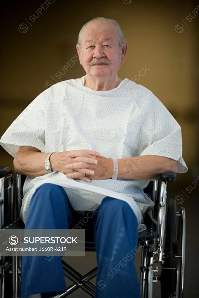 Male patient sitting in a wheelchair with his hands clasped