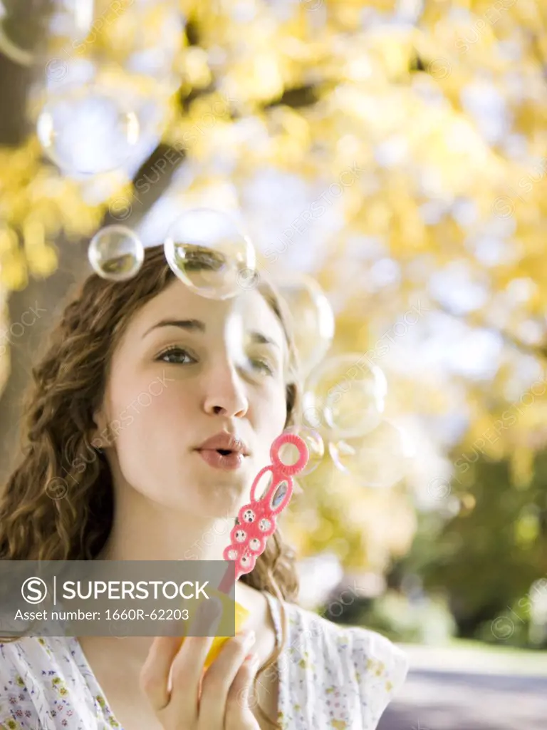 Young woman blowing soap bubbles in Autumn forest