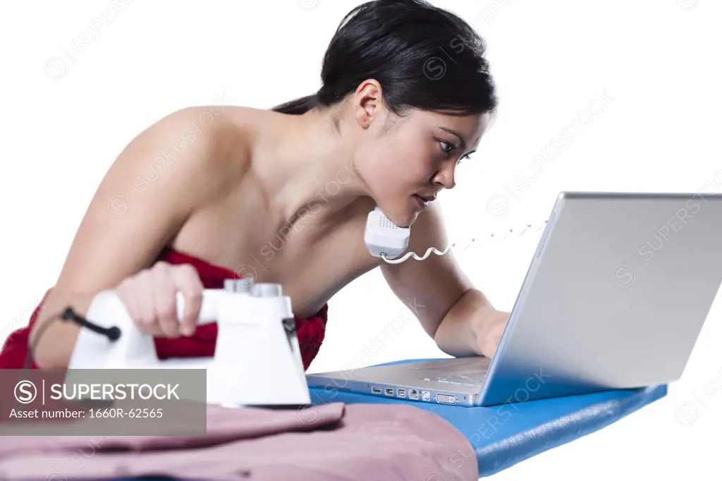 Woman ironing and working on laptop