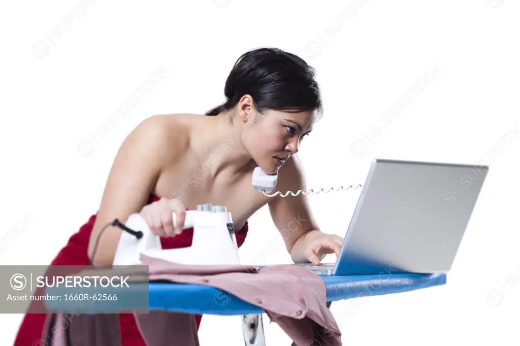 Woman ironing and working on laptop
