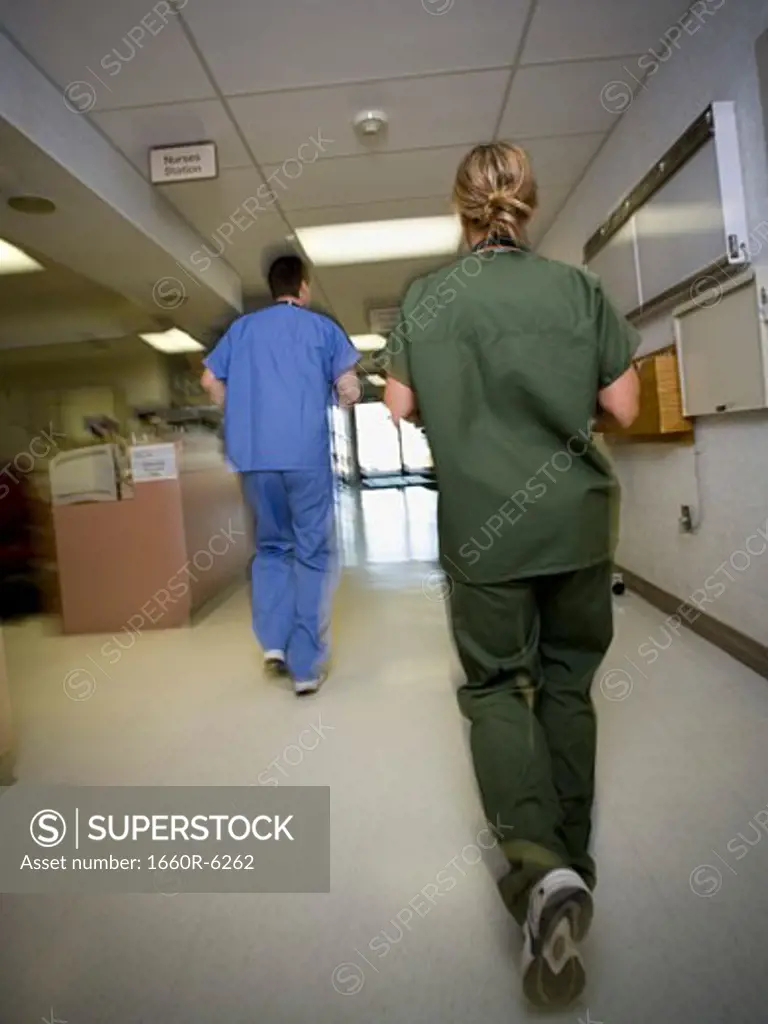 Rear view of a male doctor and a female nurse running in a hospital