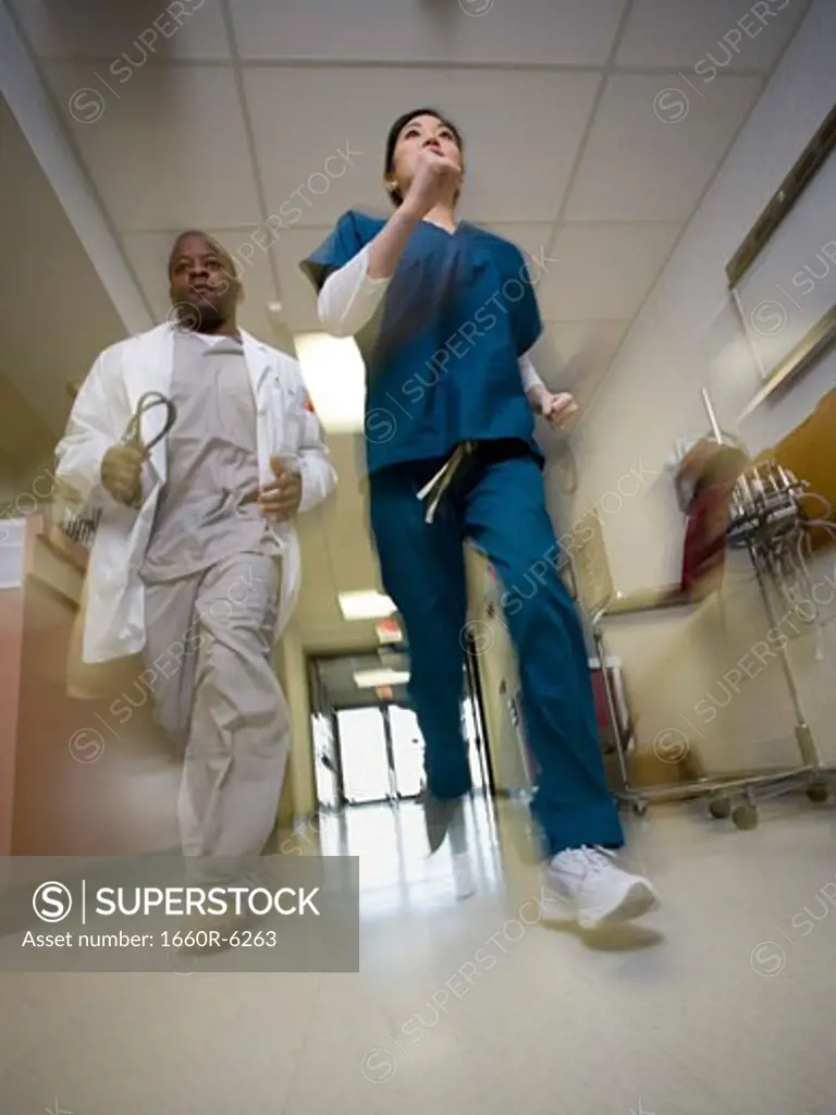 Low angle view of a male doctor and a female nurse running in a corridor