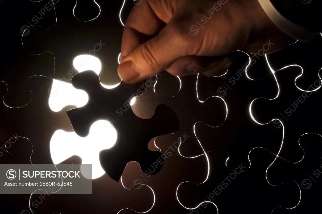 Hand inserting piece of jigsaw puzzle