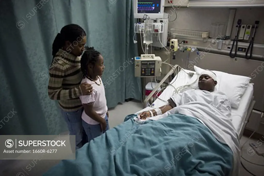High angle view of a mother and daughter in a hospital looking at a teenage boy