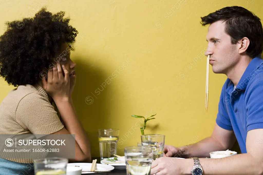 Man with chopsticks in nose at restaurant