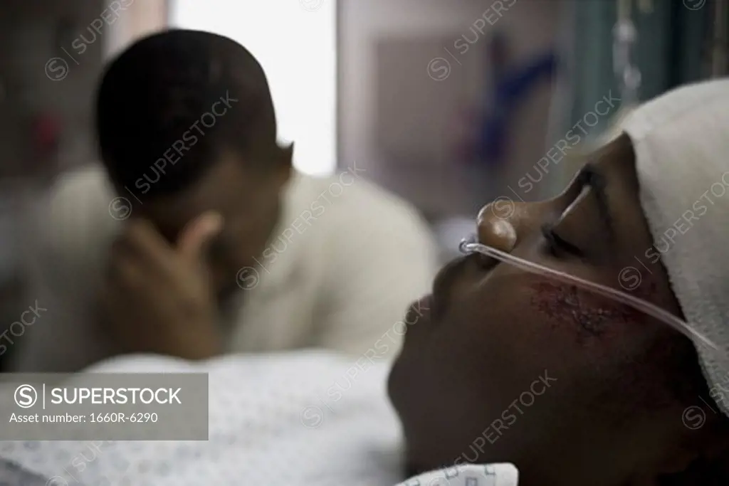 Father sitting beside his son lying on a hospital bed