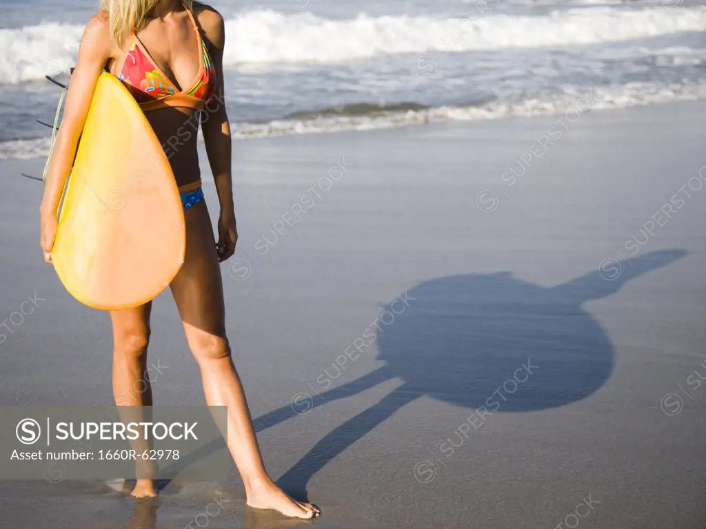 Young woman with surfboard on beach