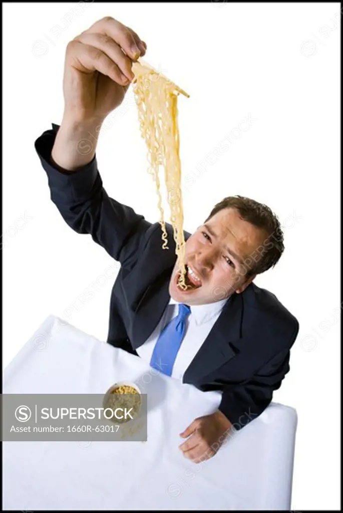 Businessman awkwardly eating noodles