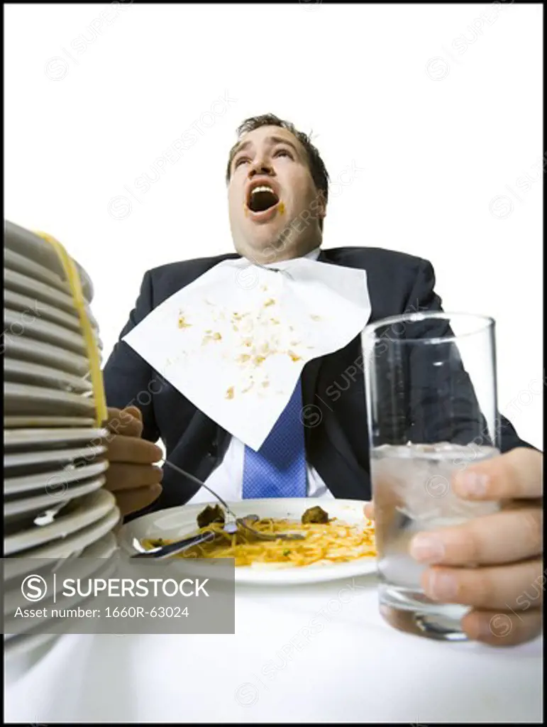 Overweight businessman gorging himself on spaghetti