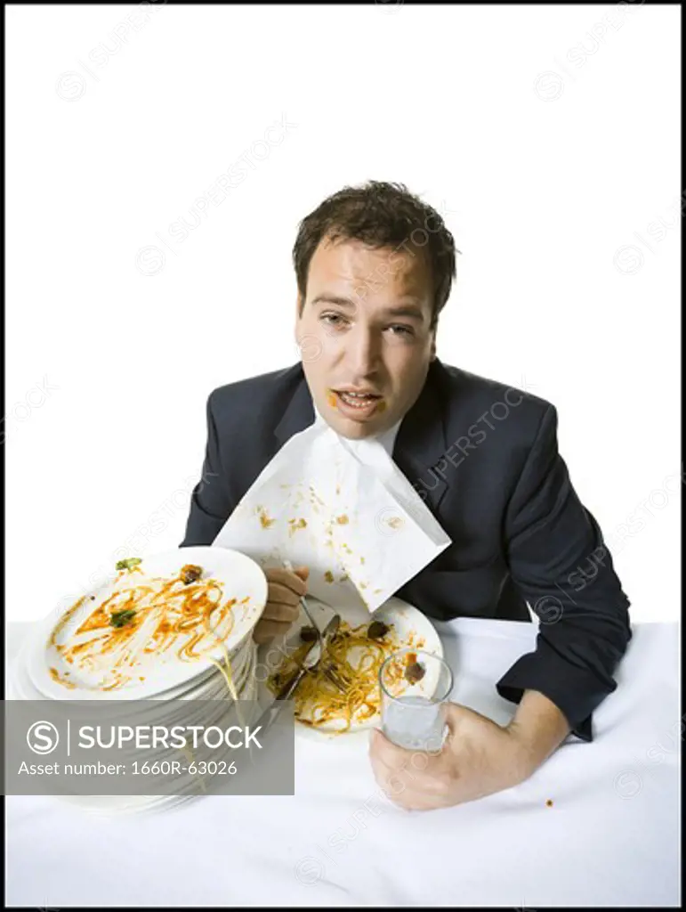 Overweight businessman gorging himself on spaghetti