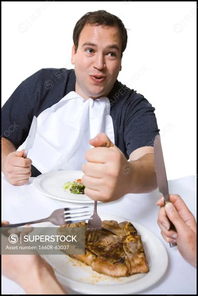 Overweight man stealing steak off partner's plate