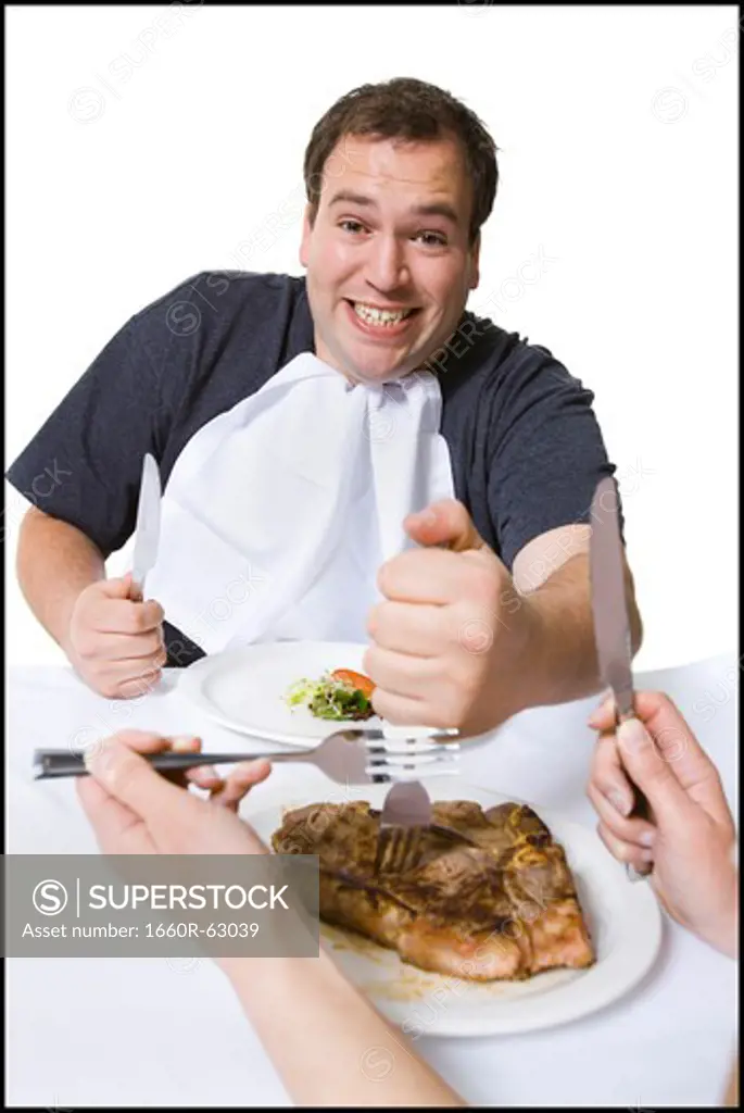Overweight man stealing steak off partner's plate