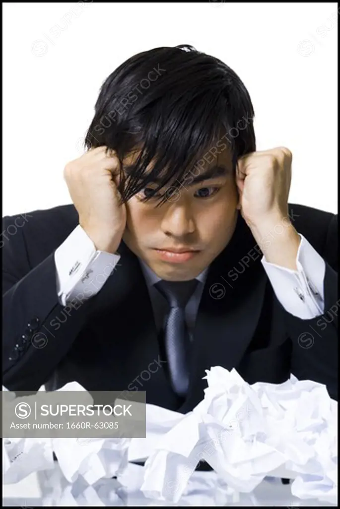 Frustrated businessman surrounded by crumpled papers