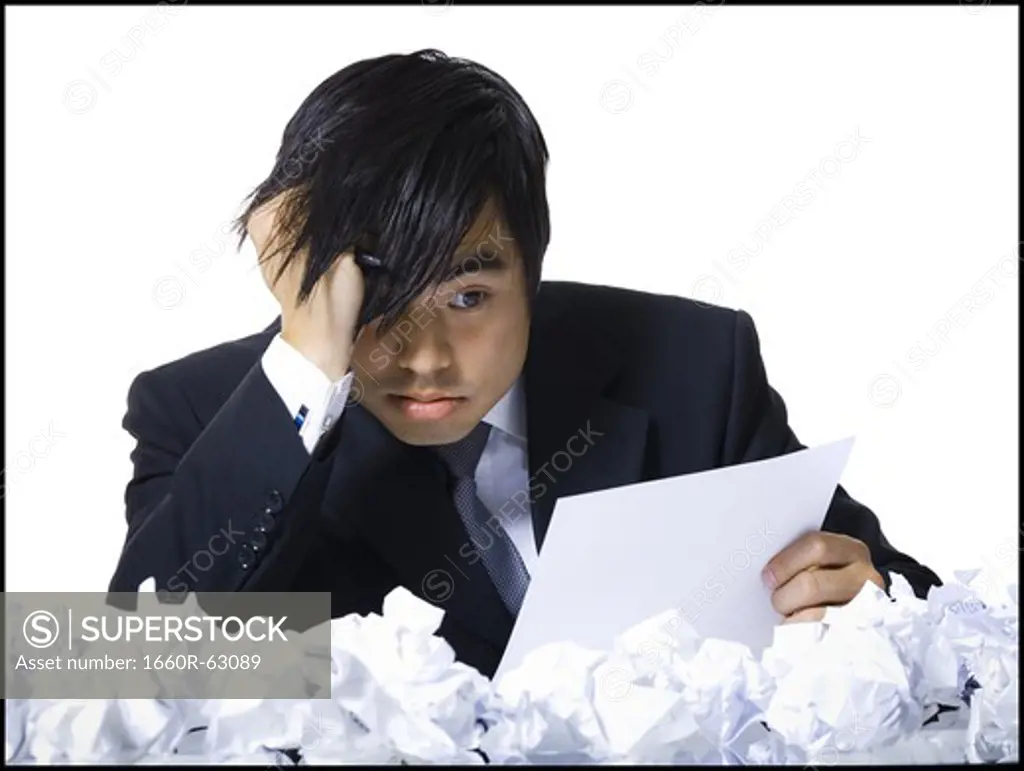 Frustrated businessman surrounded by crumpled papers