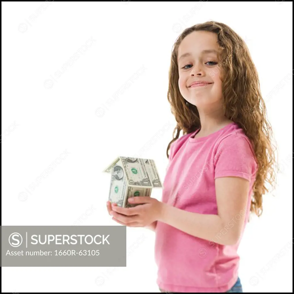 Young girl with a little house made of banknotes