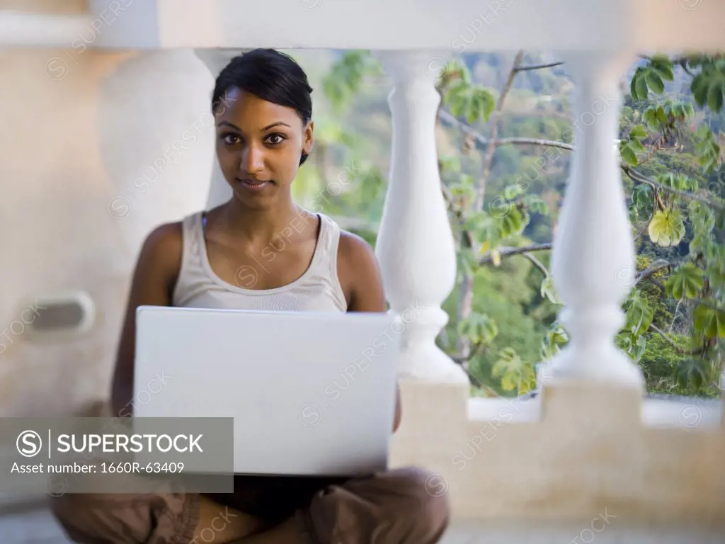 African-American woman sitting on balcony with laptop