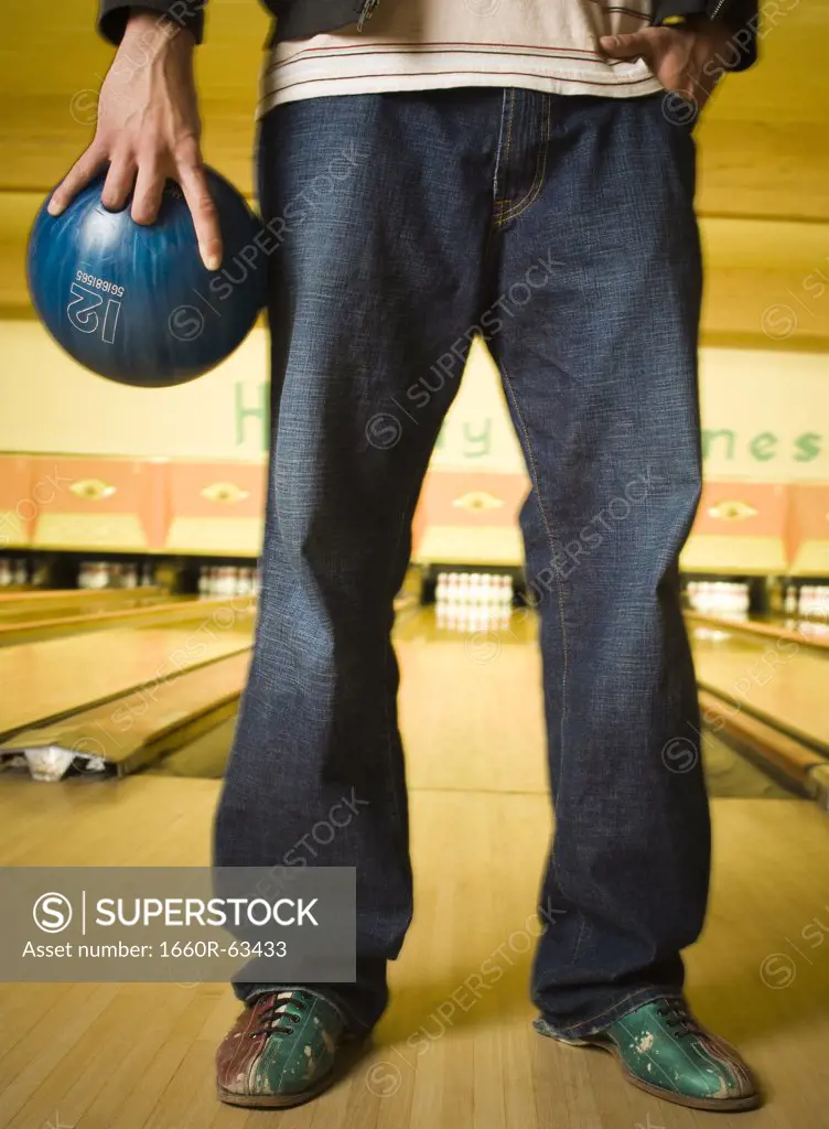 Low section view of a young man holding a bowling ball