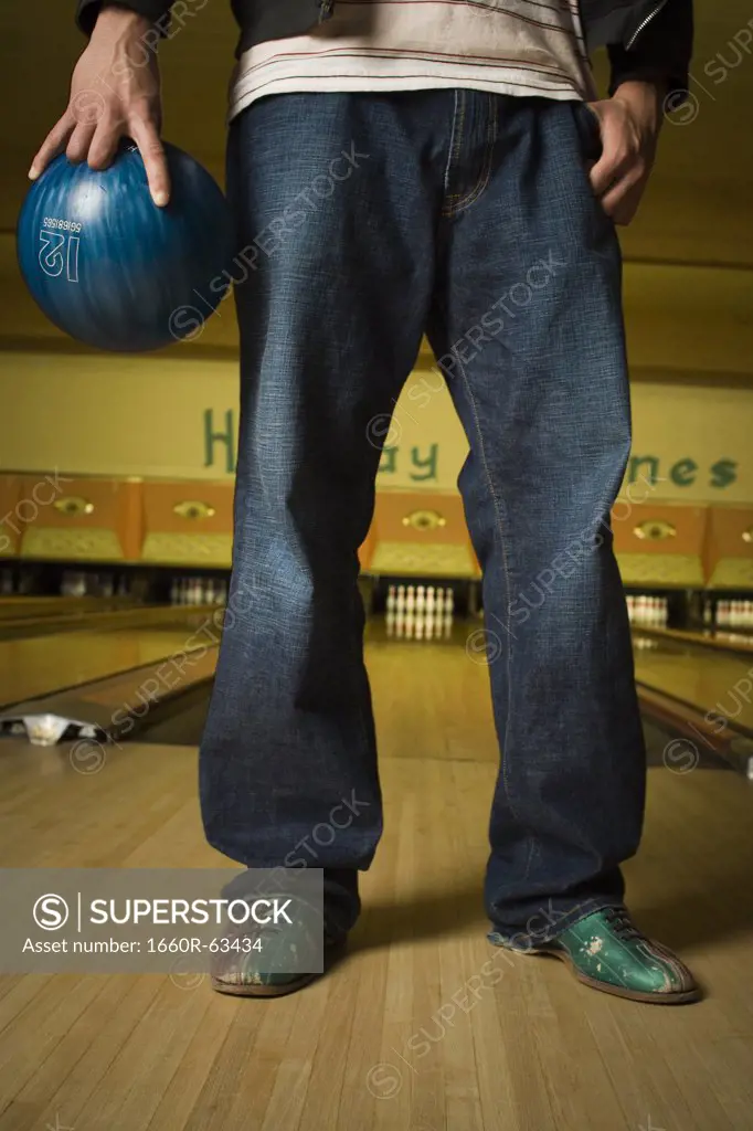Low section view of a young man holding a bowling ball