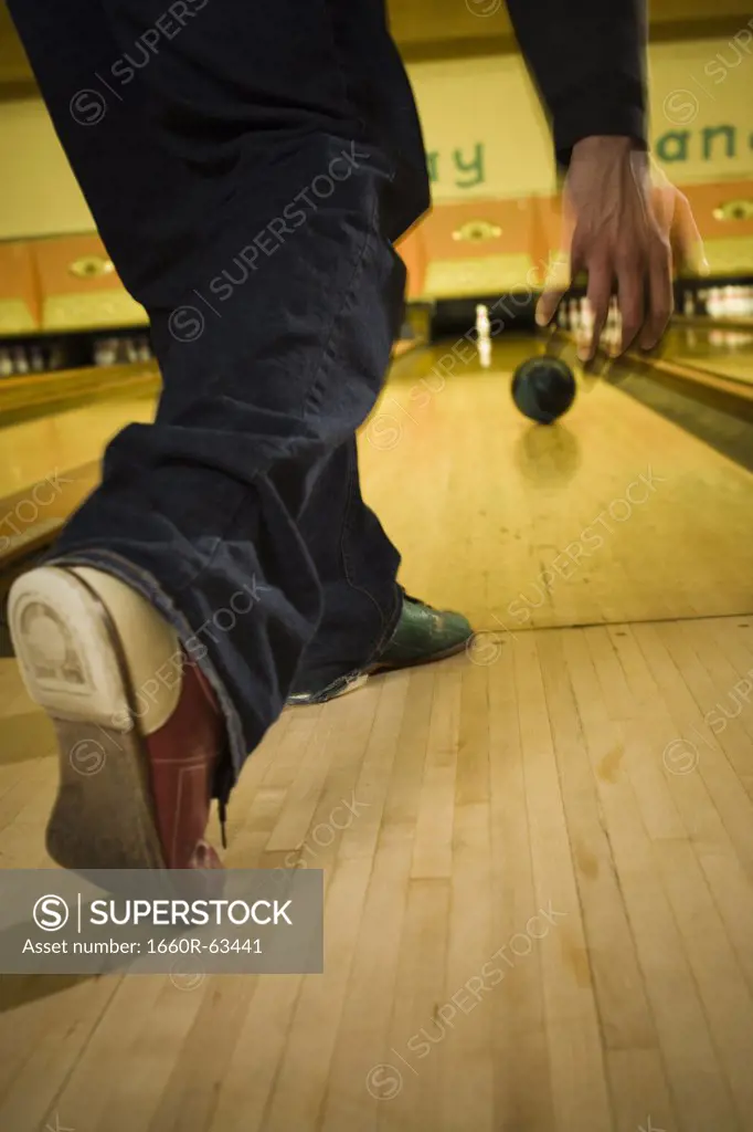 Low section view of a young man bowling at a bowling alley