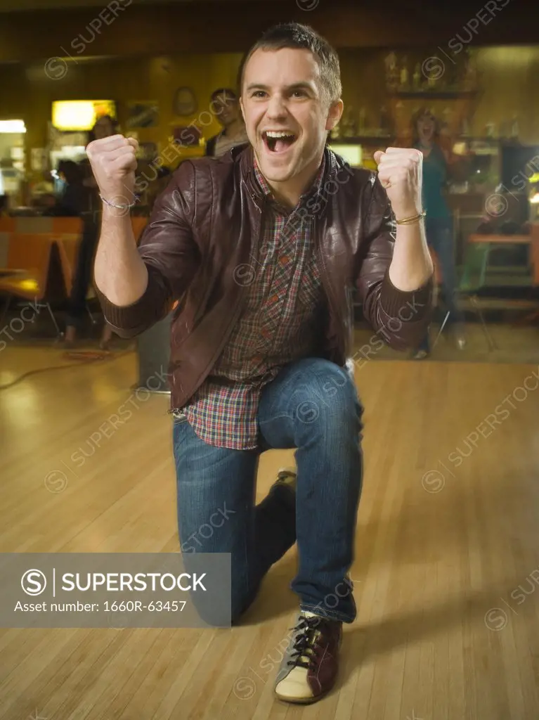 Young man with his arms raised in excitement in a bowling alley