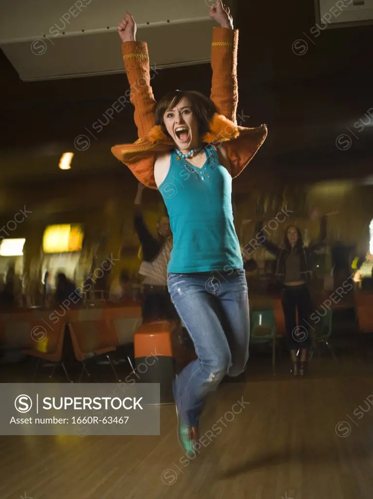 Teenage girl jumping in excitement in a bowling alley