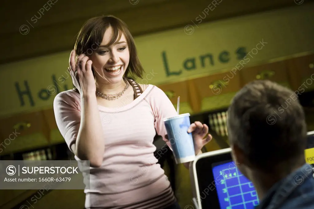 Teenage girl holding a disposable glass of cola and looking at a young man