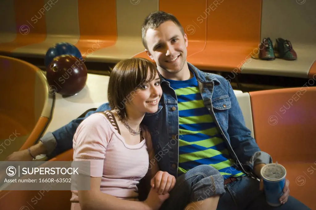 Portrait of a young man and a teenage girl sitting in a bowling alley