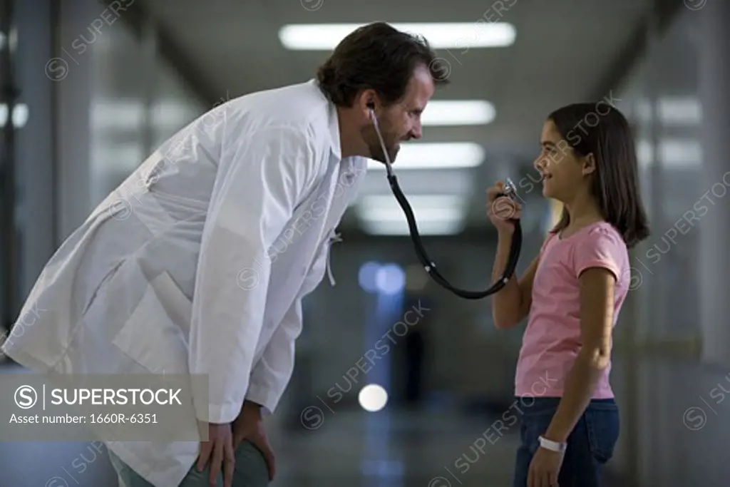 Profile of a girl talking into a male doctor's stethoscope