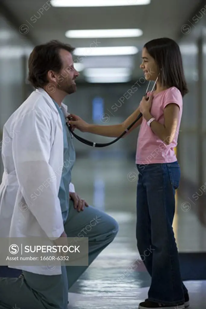 Profile of a girl checking a male doctor's heart beat with a stethoscope