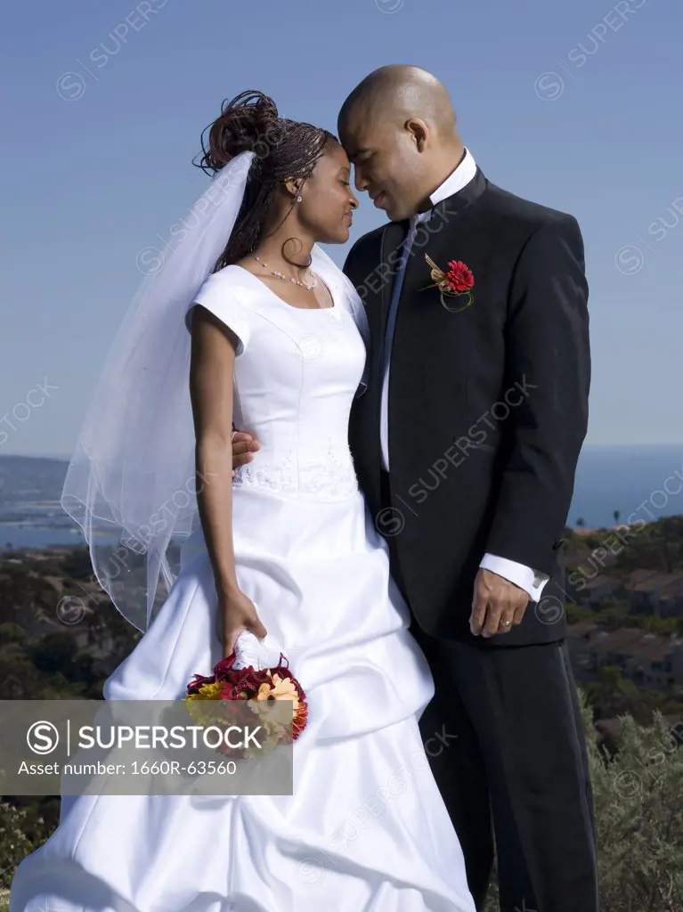 Newlywed couple standing together with their eyes closed