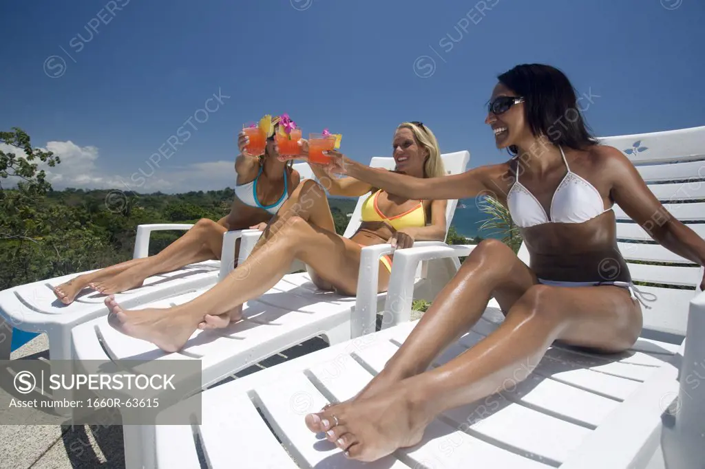 Three young woman celebrating by the pool