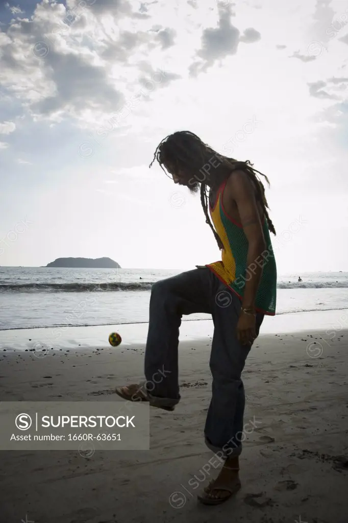 Profile of a man playing hacky sack on the beach