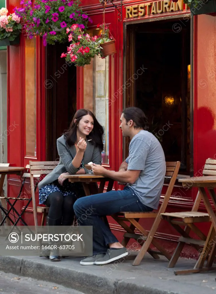 France, Couple sitting in sidewalk cafe