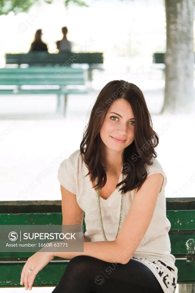 France, Paris, Portrait of young woman sitting on bench