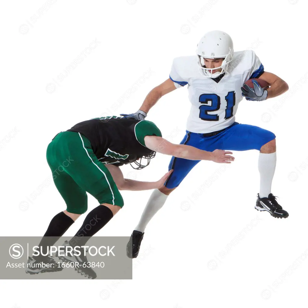 Two male players of American football fighting for ball, studio shot
