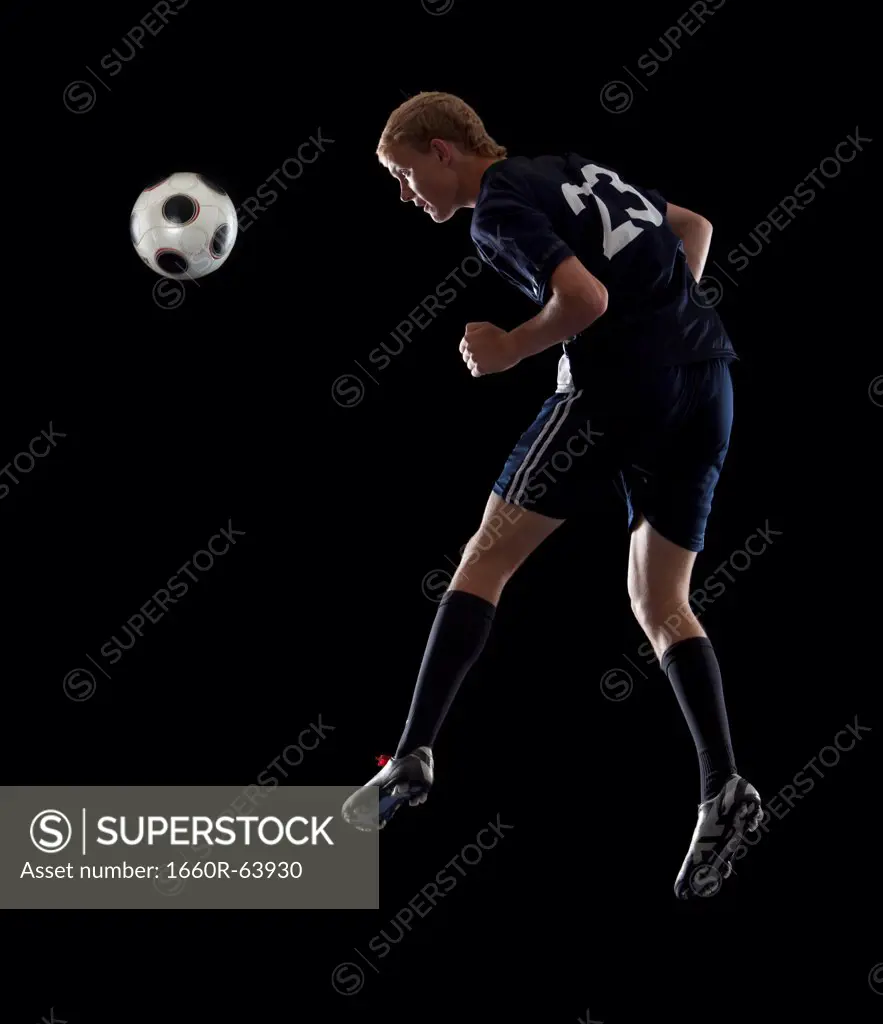 Studio portrait of teenage boy (16-17) with soccer ball