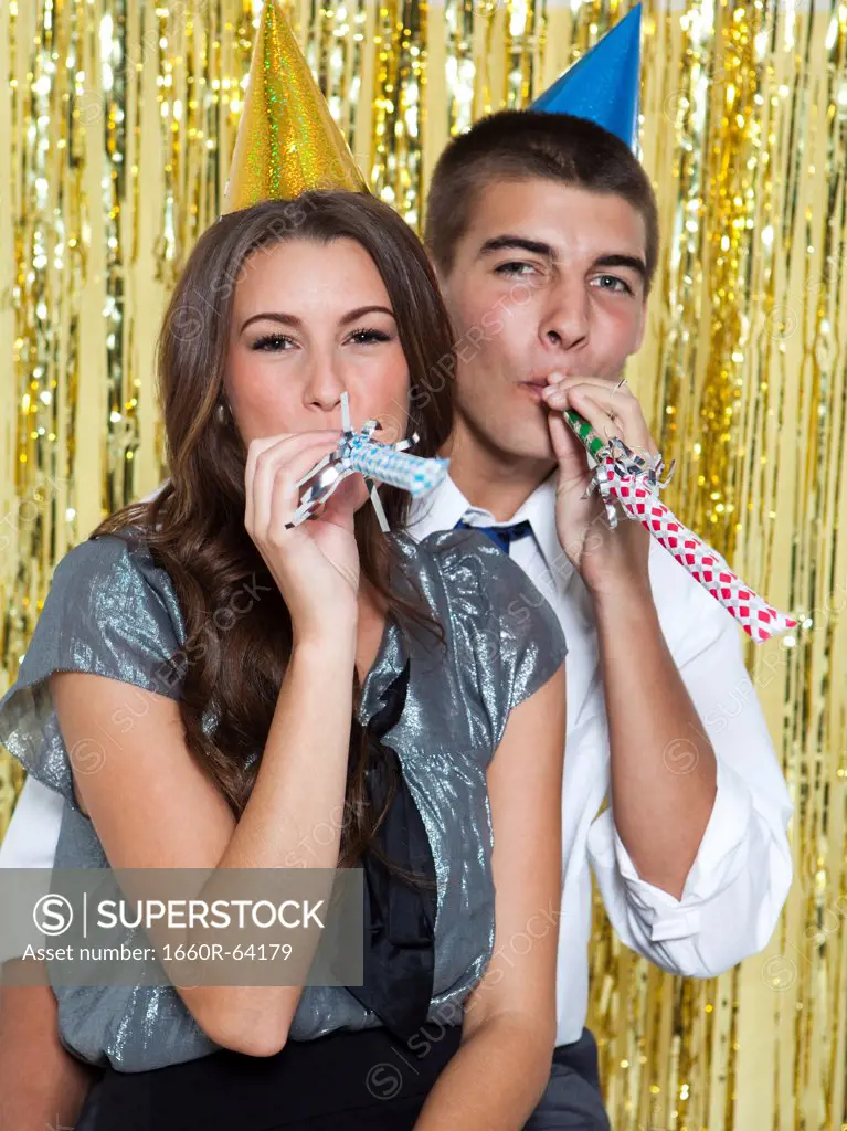 USA, Utah, Orem, Portrait of young couple blowing horns at party